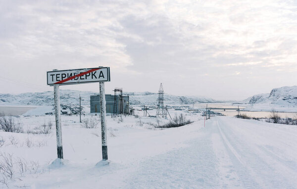 Teriberka, Murmansk region / Russia - February 2018: A road sign warns of entering the village of Teriberka in severe winter frosts under white snow decorated with various stickers from tourists