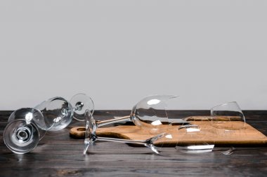 broken wineglasses and axe with wooden board on table clipart