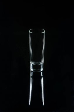 one small glass on black reflecting surface clipart
