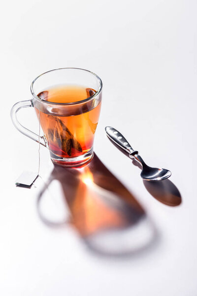 glass cup of black tea and spoon on table