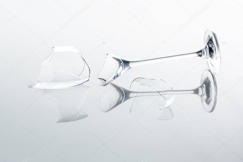 broken wineglass on white reflecting tabletop