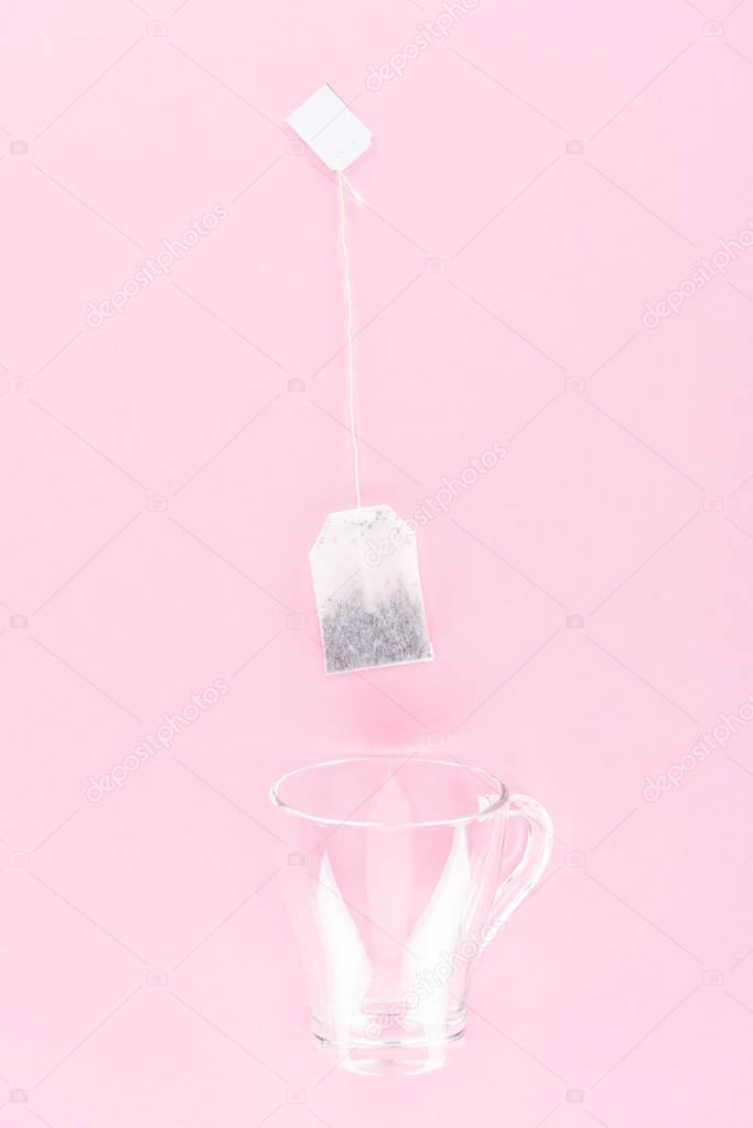 Top view of one tea bag and empty glass cup isolated on pink