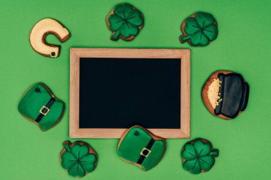 top view of empty board with icing cookies isolated on green, st patricks day concept clipart