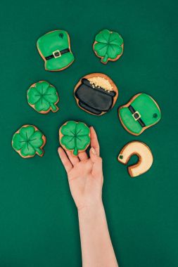 cropped image of woman holding icing cookies isolated on green, st patricks day concept clipart