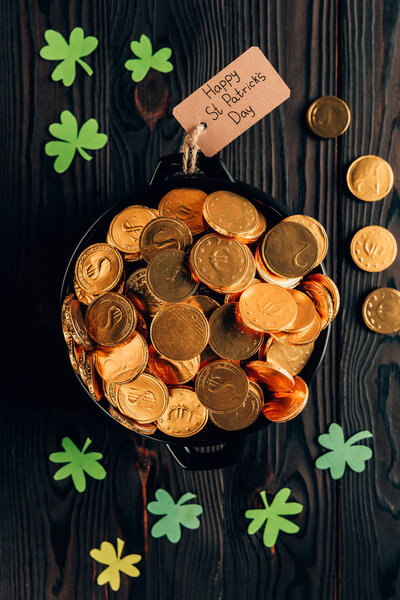 top view of pot with golden coins and shamrock on wooden table, st patricks day concept