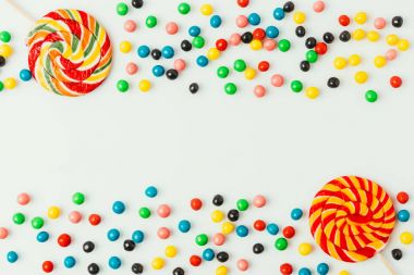 top view of arranged lollipops and candies isolated on white clipart