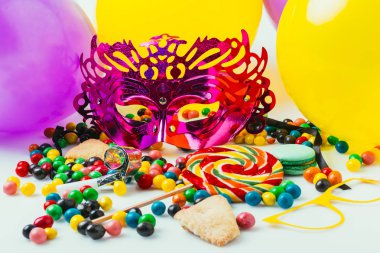 Balonlar, maskeli balo maskeleri ve şekerler, purim tatil kavramı görünümünü kapat