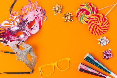 flat lay with lollipops and party objects isolated on orange, purim holiday concept