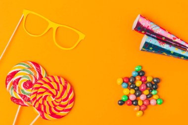düz lay tatlılar, lolipop ve portakal, purim tatil kavramı izole parti nesneleri ile