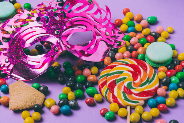 закрыть вид маски маскарад, леденец и конфеты изолированы на фиолетовый
