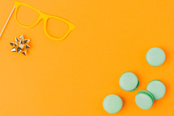 top view of party mask, bow and macarons isolated on orange, purim holiday concept