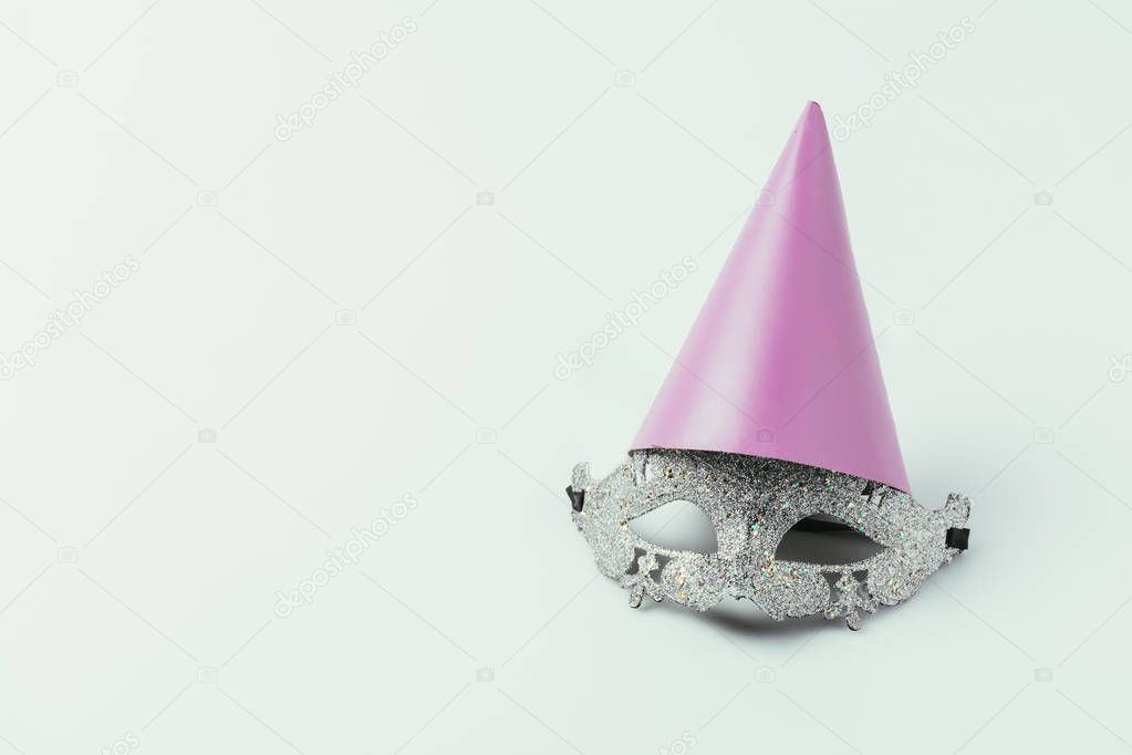 close up view of masquerade mask and party cone isolated on grey