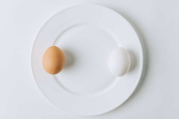 white and brown eggs laying on plate on white background