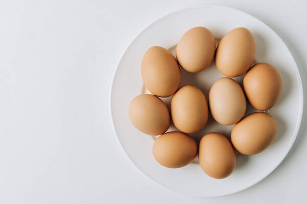 brown eggs laying on white plate on white background 