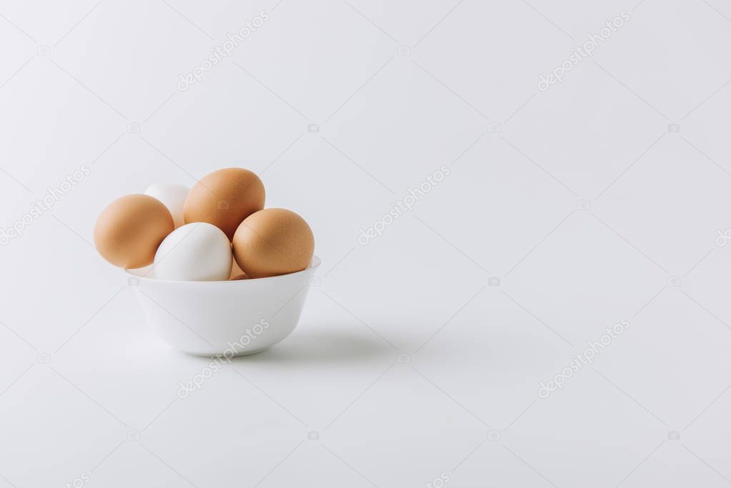  white and brown eggs laying on white plate on white background