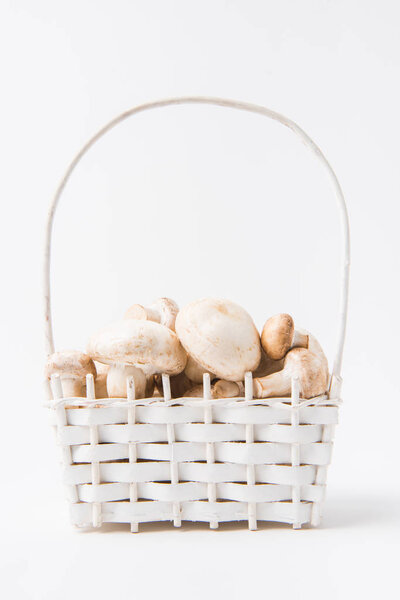 куча грибов, лежащих в плетеной корзине на белом фоне
  