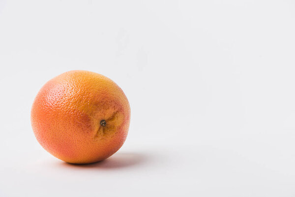 raw unpeeled orange laying on white background 