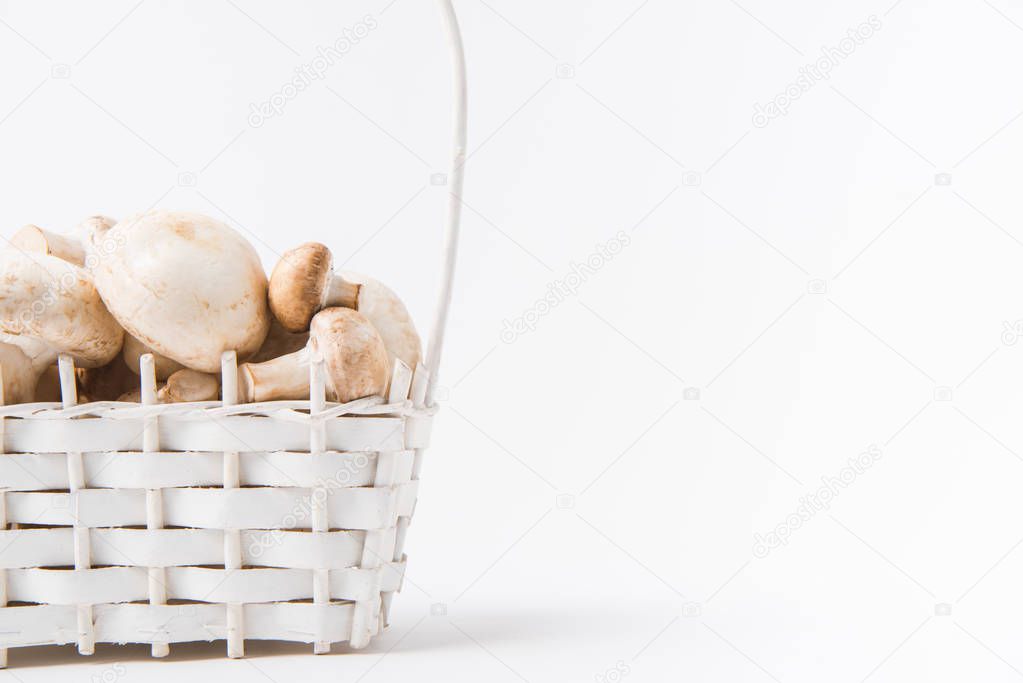 heap of mushrooms laying in wicker basket on white background  