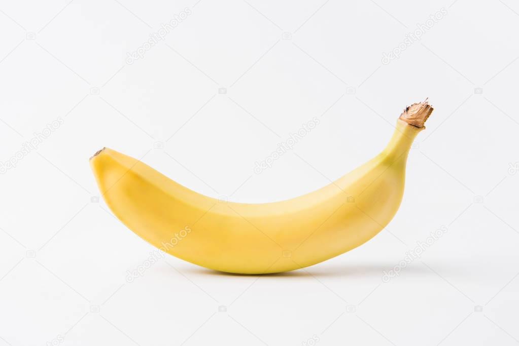 raw unpeeled banana laying on white background  