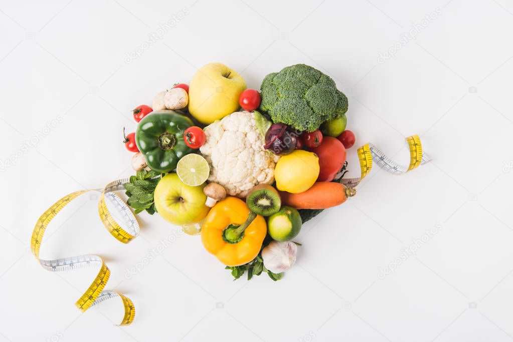 various vegetables laying on white background  with measuring tape