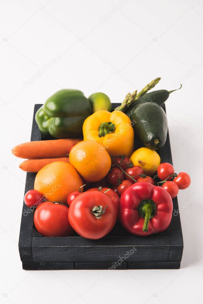 Raw colorful vegetables and fruits in dark wooden box isolated on white background