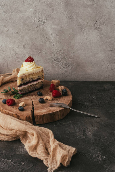 piece of delicious cake with berries and whipped cream on wooden board 