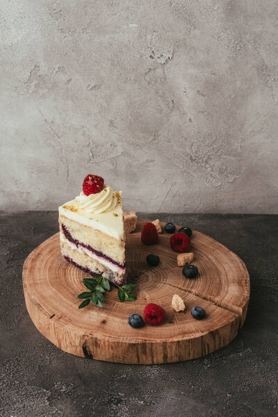piece of delicious fruity cake with whipped cream on wooden board