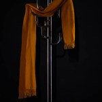 Gelber Schal hängt auf Kleiderständer isoliert auf schwarzem Grund
