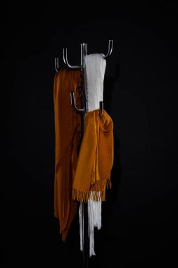 various scarves hanging on coat rack isolated on black clipart