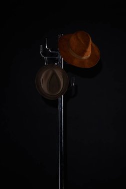 hats hanging on coat rack isolated on black clipart