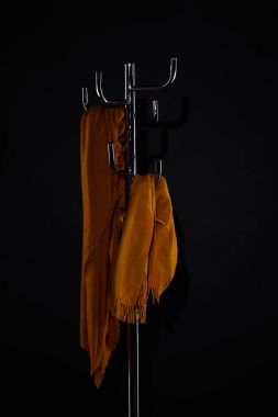 yellow scarves on coat rack isolated on black clipart