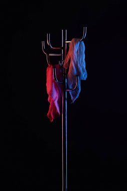 scarf hanging on coat rack under toned light isolated on black clipart