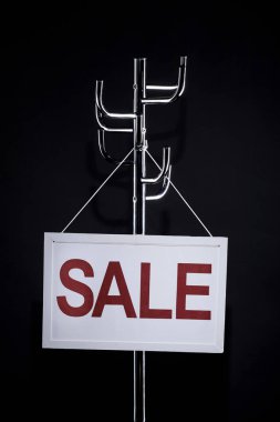 sale signboard hanging on coat rack isolated on black clipart