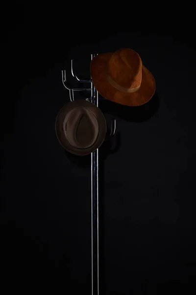 hats hanging on coat rack isolated on black