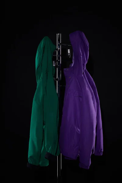 raincoats hanging on coat rack isolated on black