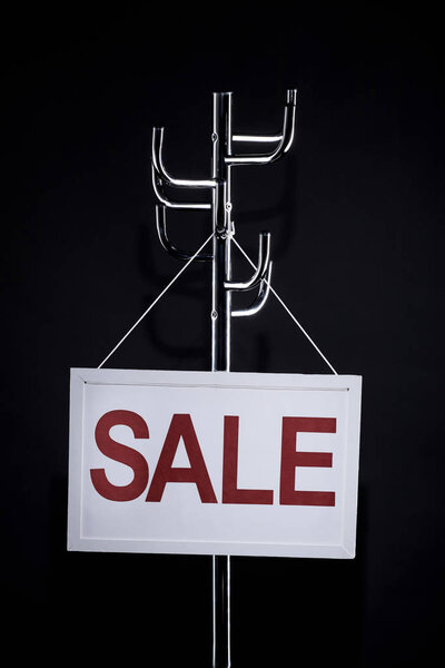 sale signboard hanging on coat rack isolated on black