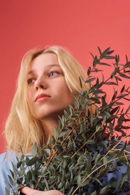 beautiful young woman with bunch of eucalyptus branches isolated on red clipart