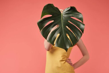 genç kadın kırmızı izole monstera yaprak ile yüz kapsayan