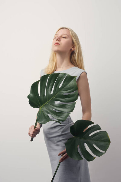 beautiful young woman with monstera leaves isolated on white