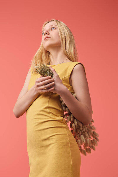 attractive young woman with bouquet of Lagurus looking up isolated on red