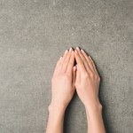 Oříznout záběr ženských rukou na šedém povrchu betonu