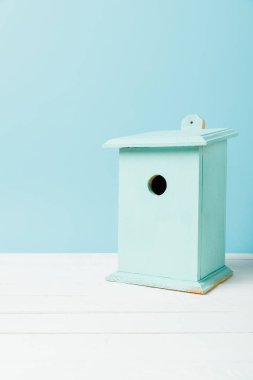 close up view of blue birdhouse on wooden surface isolated on blue clipart