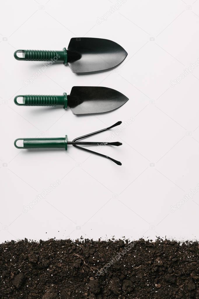 top view of arranged gardening tools and ground isolated on white
