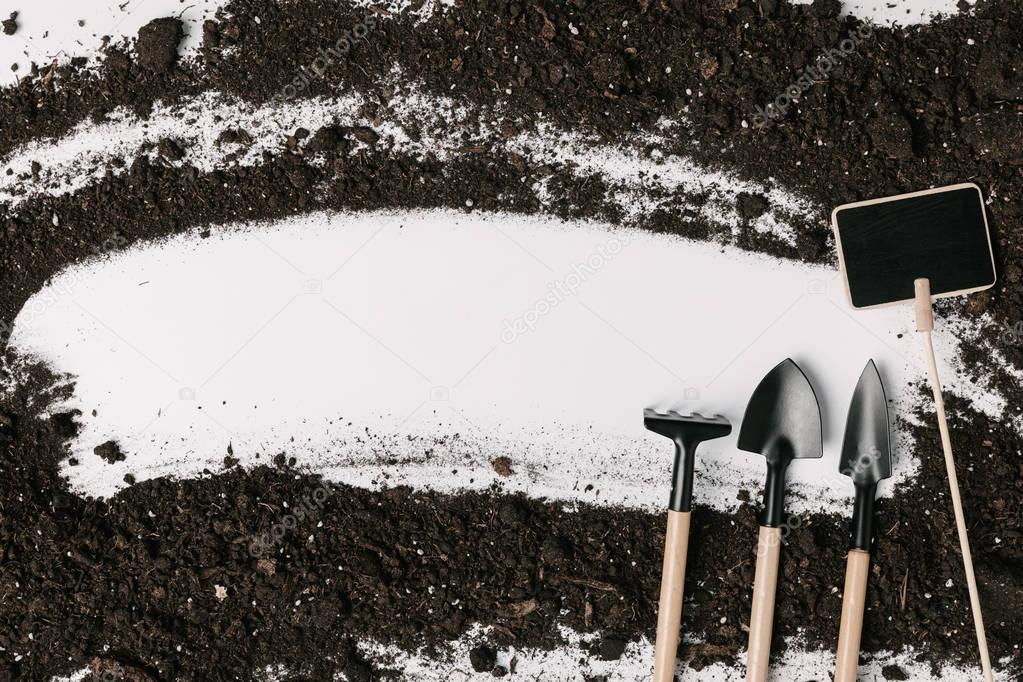 top view of arranged gardening equipment, empty blackboard and soil isolated on white
