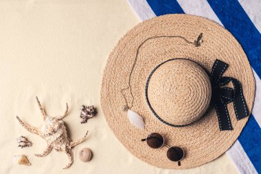 Straw hat with sunglasses and seashells on sandy beach clipart