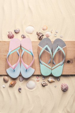 Flip flop ve deniz kabuklarını hafif kum üzerinde ahşap iskele üzerinde