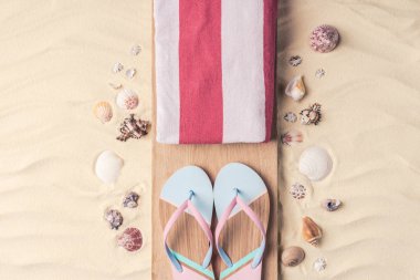 Hafif kum üzerinde flip flop ve kabukları ile havlu