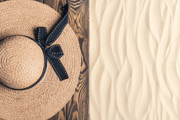 Straw hat on wooden pier on sandy beach