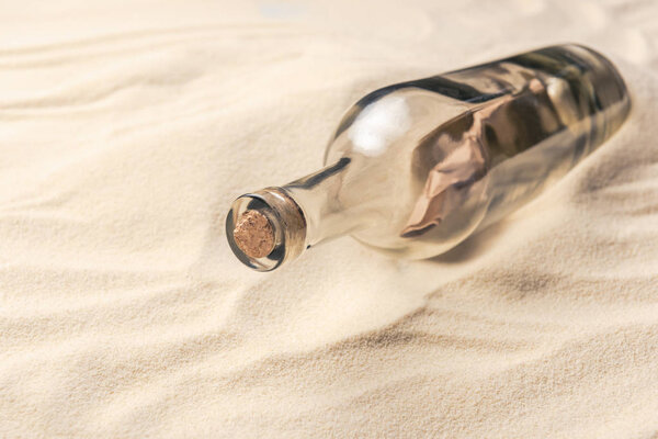 Corked bottle with message on sandy beach