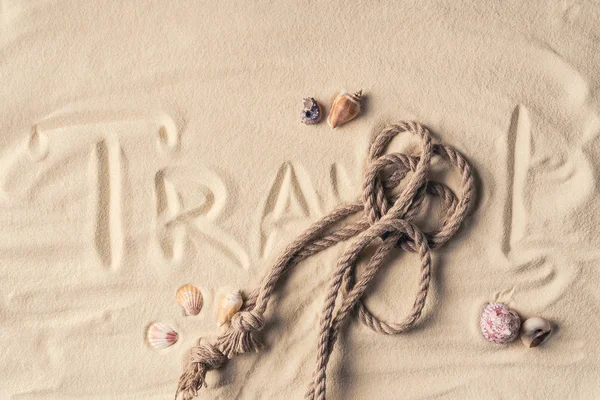 绳索和贝壳在沙滩与绳索和旅行题字 — 图库照片